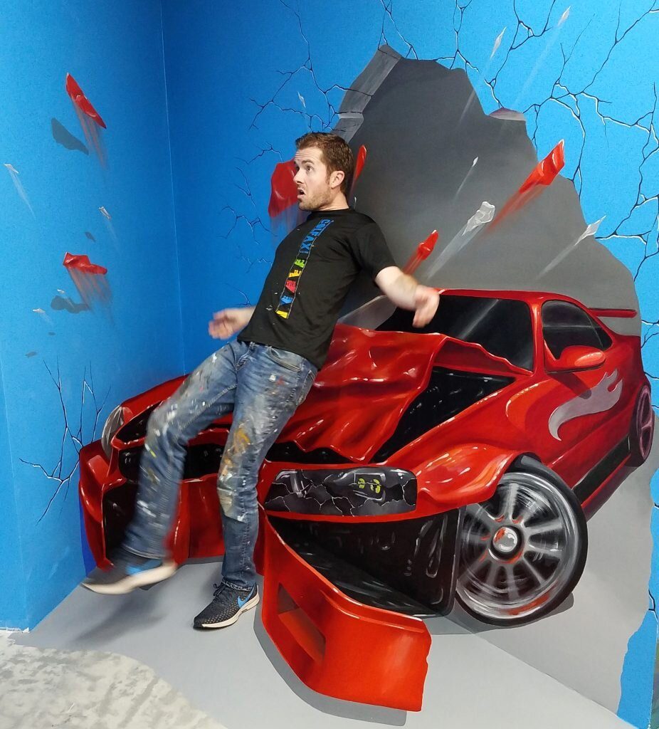 3D mural of a car crashing through a wall, an anamorphic illusion painting by Chris Carlson in San Francisco, California